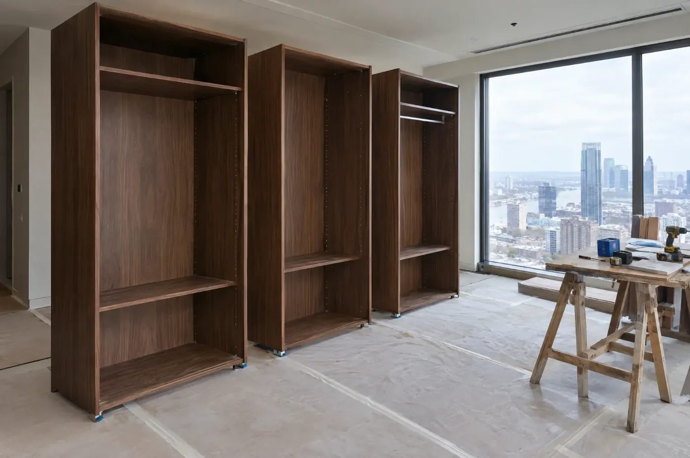 Concept visualisation: an empty bedroom on a high floor, with three walnut wardrobe modules standing on protected flooring