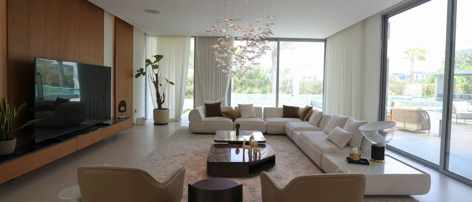 Photograph: living room at Villa 47 Fairways, Dubai Hills: a long sofa, timber media wall and garden glazing