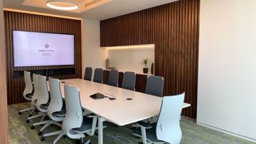 Meeting room at International Materials, Opus by Omniyat: a white table, timber-slatted walls and a screen
