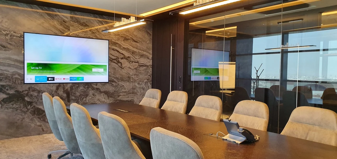 Photo: a meeting room with a grey marble feature wall, a dark timber table and a glass-walled room beyond, overlooking the city