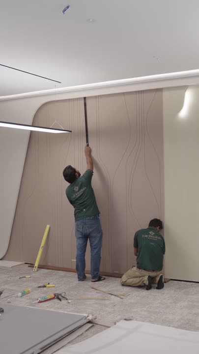 Fajr site team fitting acoustic wall panels and finishing a lit ceiling cove on an office floor, Dubai