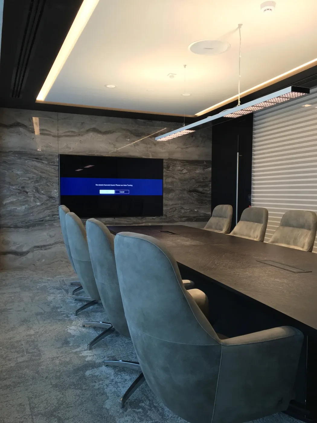 Boardroom with a stone feature wall, long table and grey chairs, delivered by Fajr Interiors for ASI, Dubai