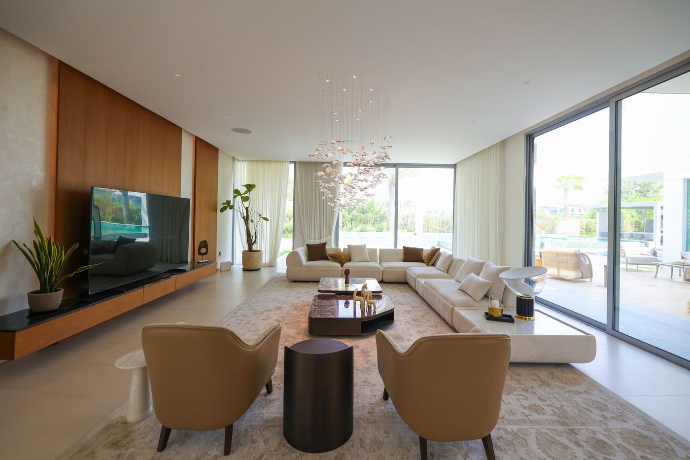 Villa 47 Fairways living room delivered by Fajr Interiors: a long sofa, timber media wall and garden glazing, Dubai Hills