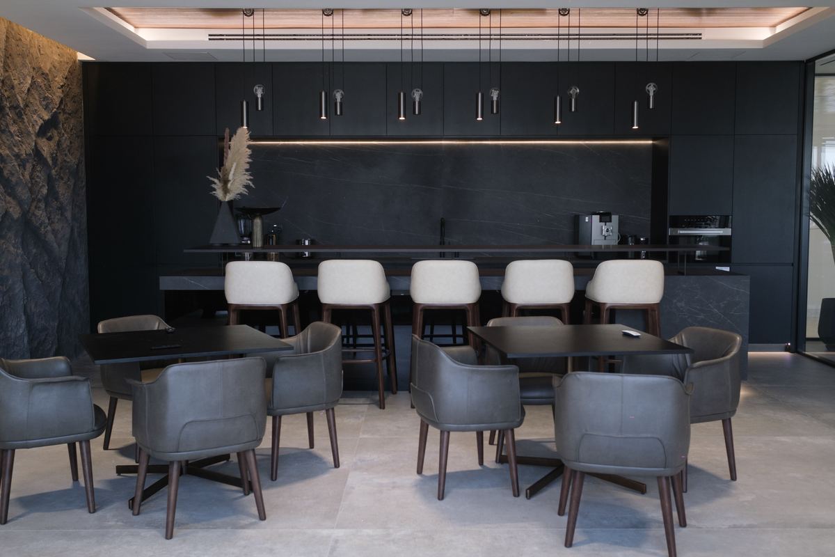 Executive pantry and dining area with a dark stone kitchen and bar seating, delivered by Fajr Interiors, Dubai