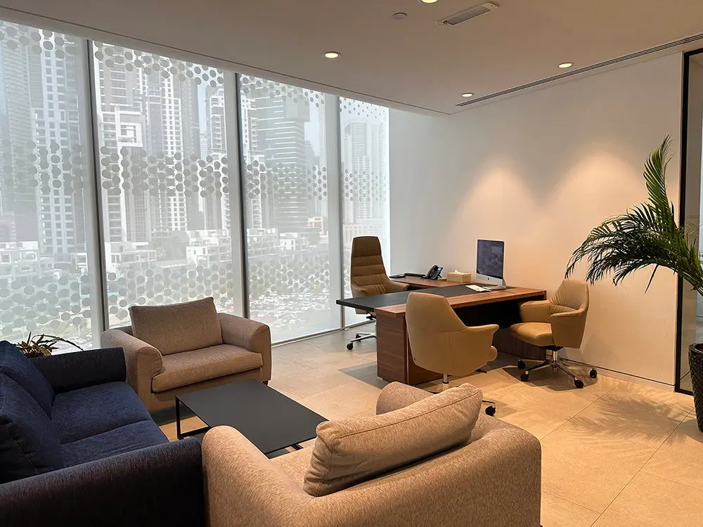 Executive office with a desk, lounge chairs and a patterned façade screen, delivered by Fajr Interiors for Global Textiles, Opus Tower, Dubai