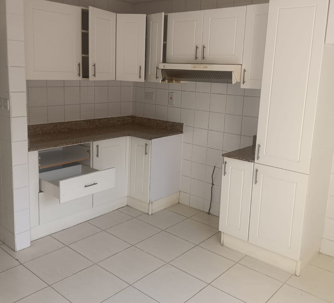 A kitchen in a Springs villa as built: white shaker cabinets, a granite worktop and a closed corner layout