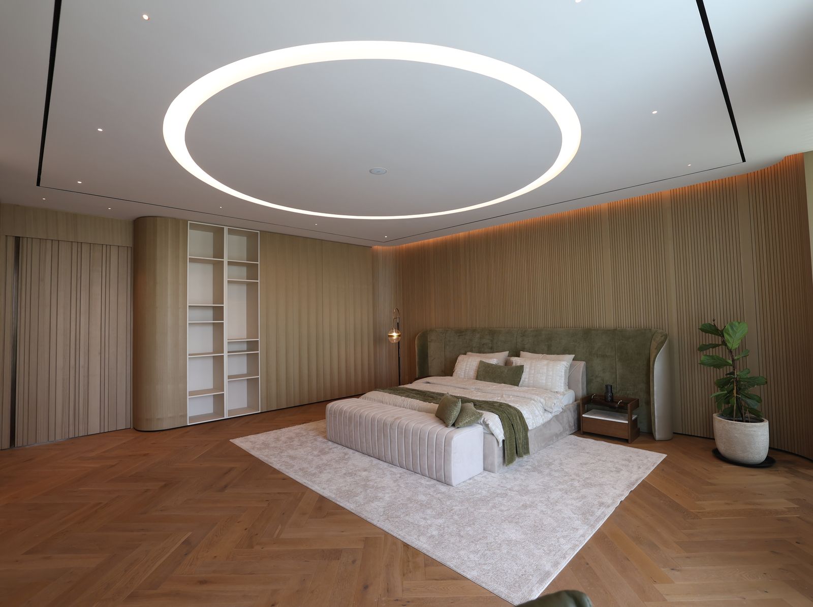 Principal bedroom with a fluted timber wall, an upholstered headboard, a herringbone oak floor and a lit ceiling ring, delivered by Fajr Interiors, Dubai