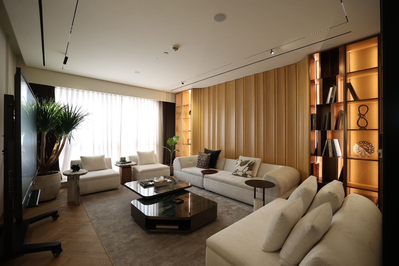 Executive lounge with fluted timber wall, lit shelving and pale sofas, delivered by Fajr Interiors, Dubai