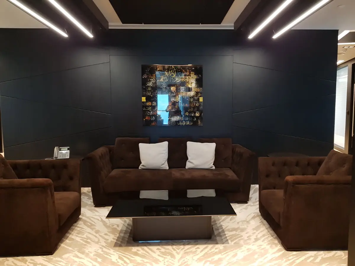 Client lounge with leather sofas and a feature artwork, delivered by Fajr Interiors for ASI, Dubai