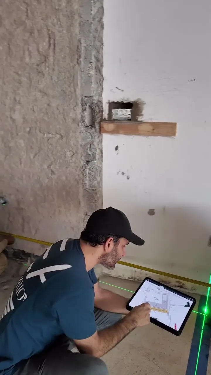 Zeeshan Patel checking the layout drawing on a tablet against a laser line on the floor of the Fajr Interiors HQ