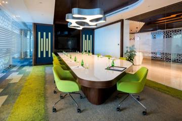 Boardroom with a long white table and green chairs, SBC office, Dubai