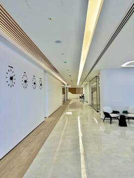 A corridor at Crypto One: a lit timber ceiling strip over a white stone floor