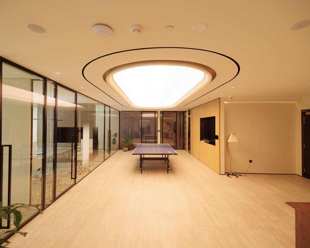 Ambient light in a Fajr office: a lit ceiling coffer over a glass-walled room with a timber floor