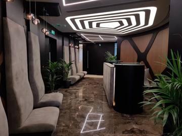 Reception lounge with a sculpted lit ceiling and grey armchairs, delivered by Fajr Interiors for ASI, Dubai