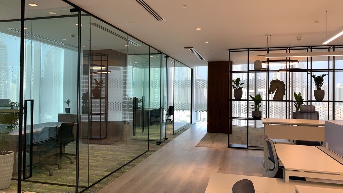 International Materials office at Opus by Omniyat: glass-walled offices along a timber-floored corridor with a screen shelf
