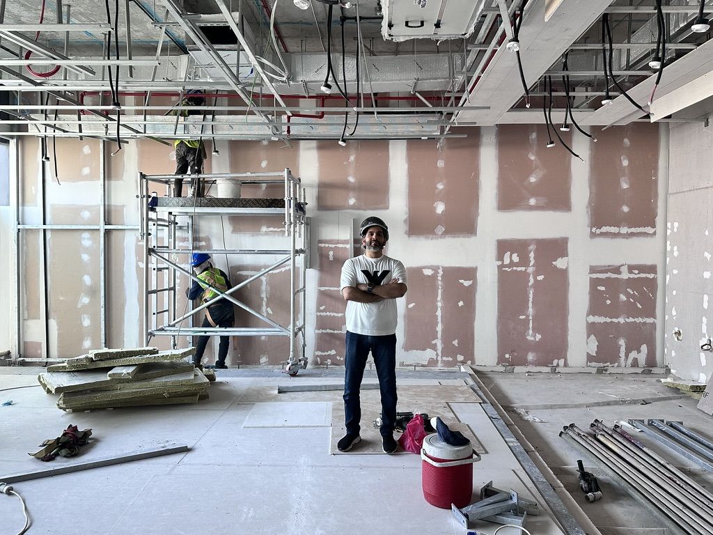 A villa stripped back for new AC and MEP on a Fajr site: open ceiling, scaffold and the site lead on the floor