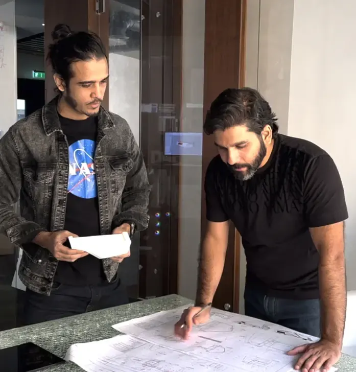 Two members of the Fajr Interiors team reviewing printed drawings in the studio, Dubai