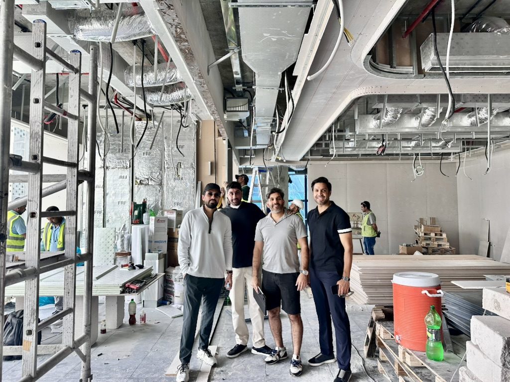 Fajr Interiors team walking the Opus Tower office during the build, ducts and ceiling framing overhead and the site team at work behind