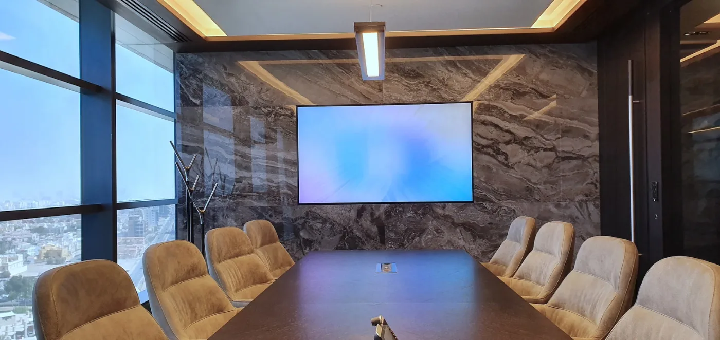 Boardroom with a stone wall and a presentation screen, delivered by Fajr Interiors for AlSubeai Investments, Jeddah