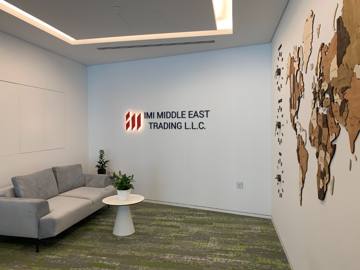 Reception at International Materials, Opus by Omniyat: a lounge corner, the company sign and a timber world-map wall