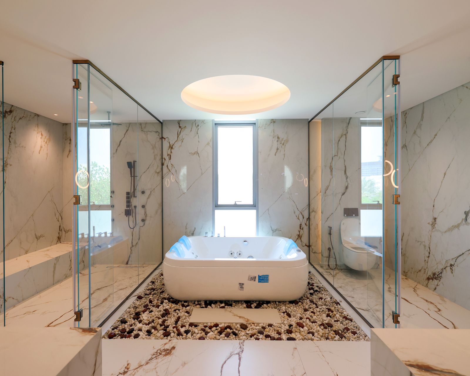 Finished principal bathroom at Villa 47 Fairways: a freestanding bath under a lit ceiling, glass-walled shower and WC, marble walls