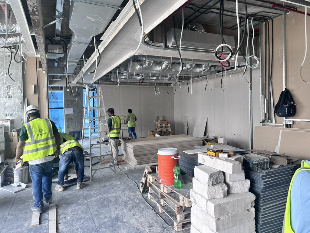 Fajr Interiors site team in hi-vis vests building drywall partitions and ceiling bulkheads in the Opus Tower office