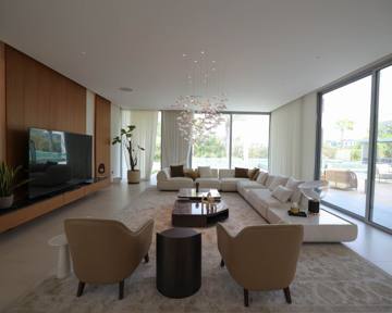 Living room at Villa 47 Fairways: a long sofa, timber media wall and garden glazing