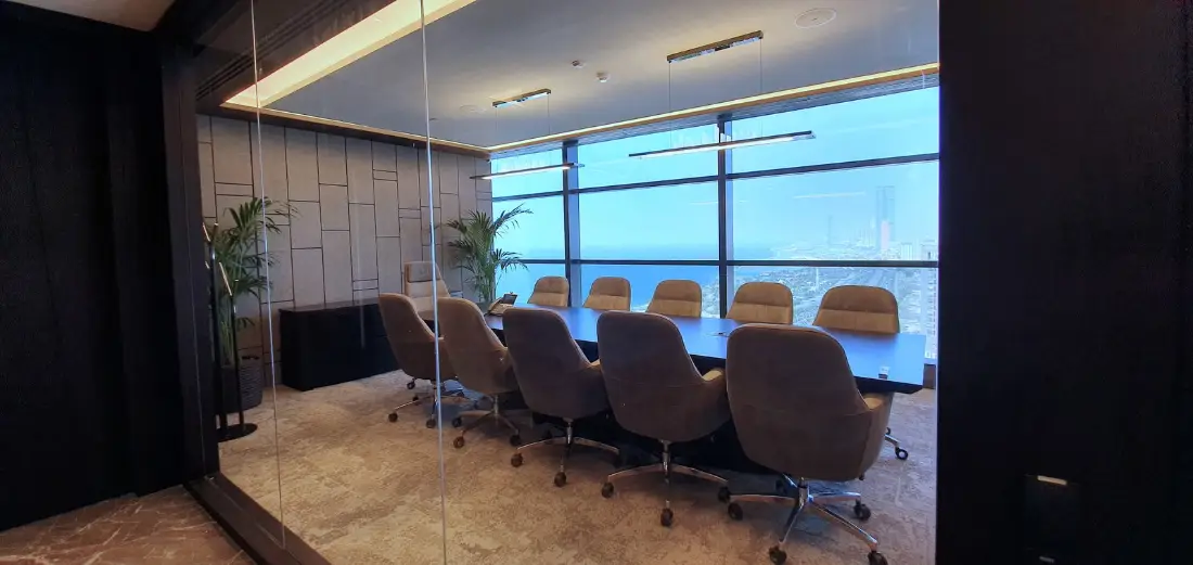 Glass-walled boardroom with a long table and a city view, delivered by Fajr Interiors for AlSubeai Investments, Jeddah