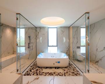 Principal bathroom at Villa 47 Fairways: a freestanding bath between glass-walled shower and WC, marble walls