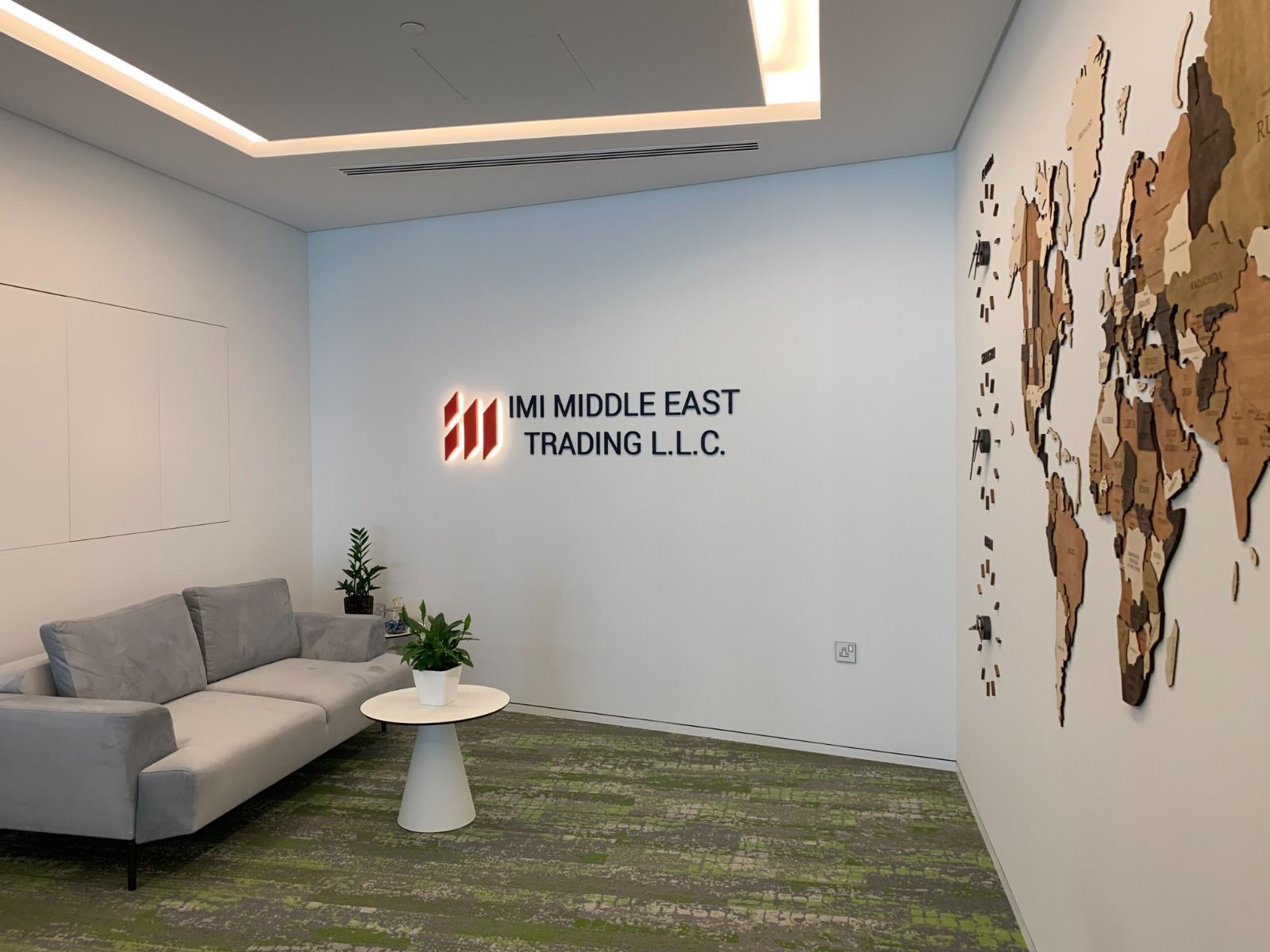 Reception at International Materials, Opus by Omniyat: a lounge corner, the company sign and a timber world-map wall