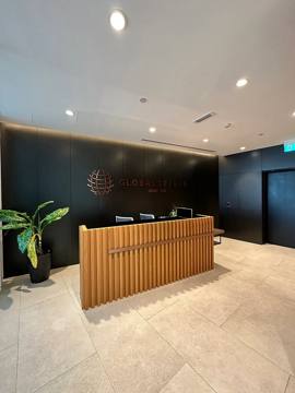 Fluted timber reception desk against a dark panelled wall, Global Textiles office, Opus Tower, Dubai