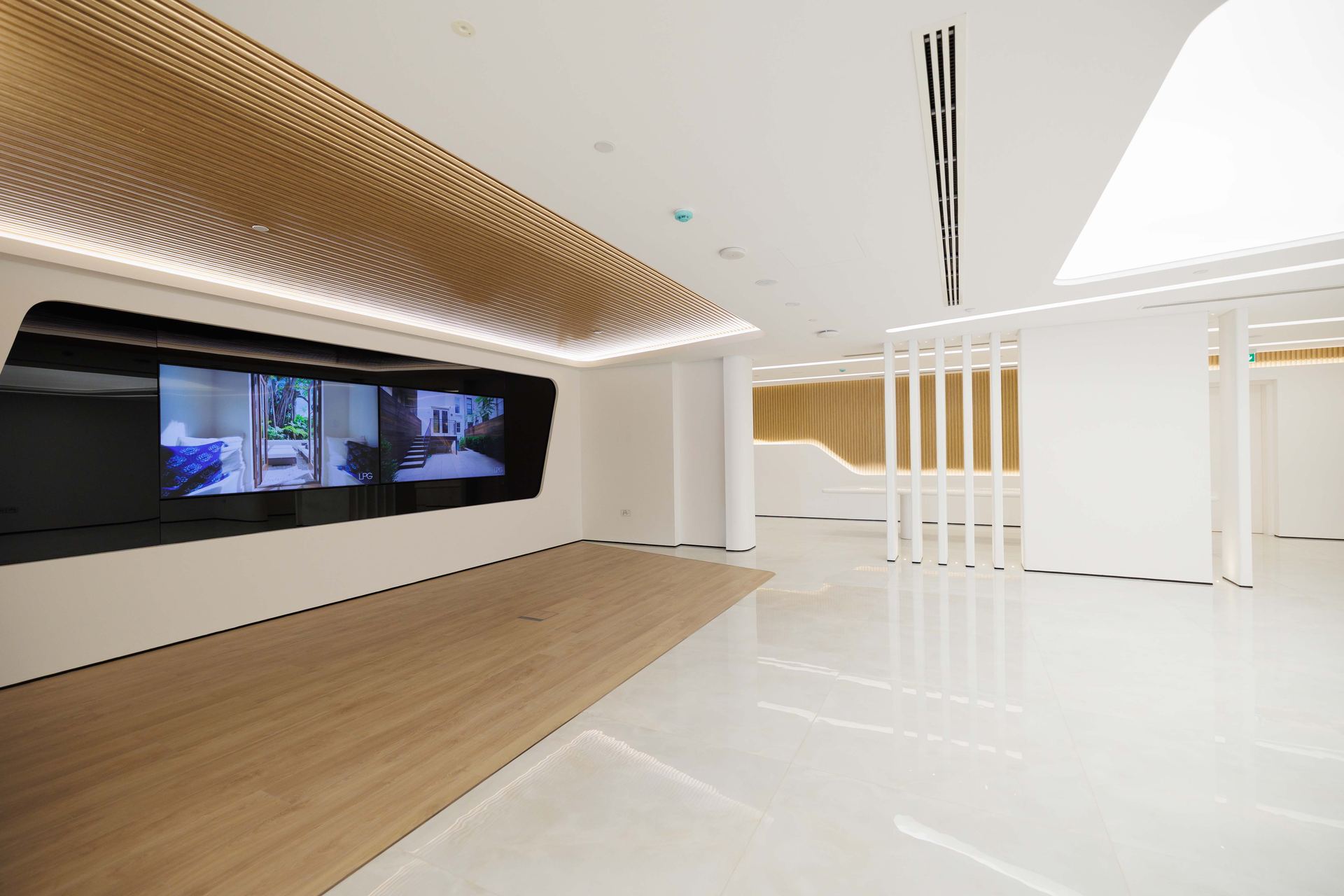 Crypto One office by Fajr Interiors, Sheikh Zayed Road: a timber-slatted ceiling over a gallery wall of screens and a white stone floor