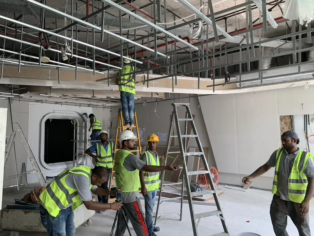 Photograph: Fajr team on ladders and at a tripod laser setting out a ceiling on an office floor under construction