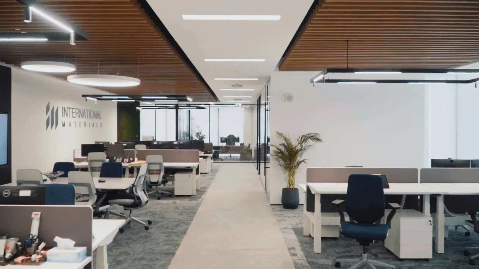 Still from the walkthrough film: the open work floor under the timber-slatted ceiling, IMI at One Za’abeel