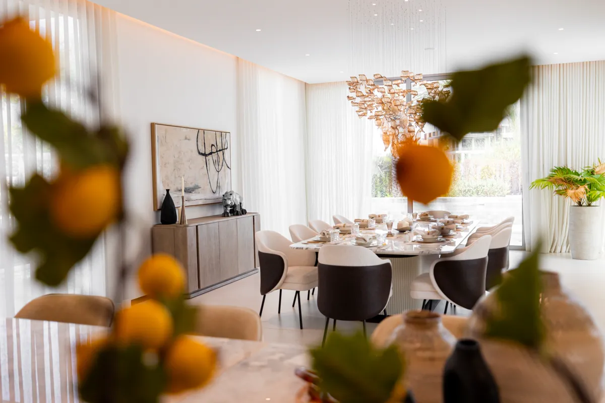 Dining room at Villa 47 Fairways, Dubai Hills: a marble table set for ten under a glass petal chandelier
