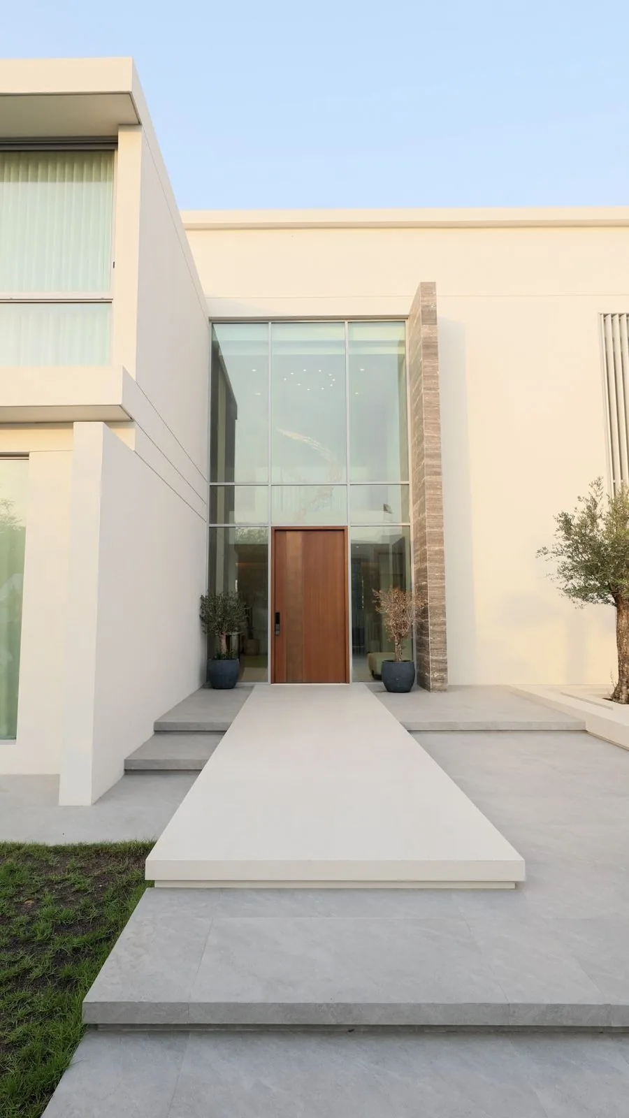 Photograph: Villa 47 Fairways, Dubai Hills: the front entrance, a timber pivot door under a glass-and-stone facade