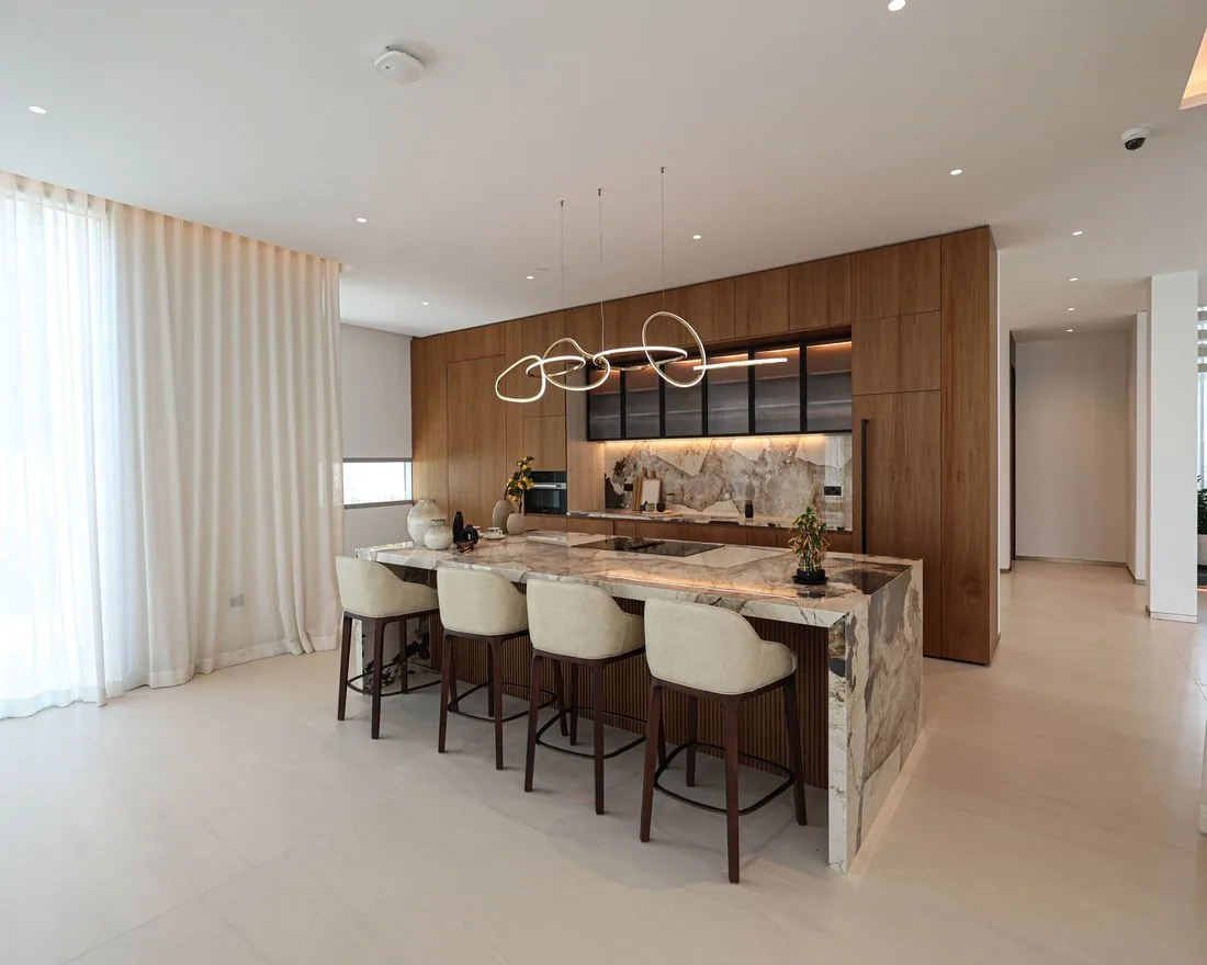 Photograph: Kitchen at Villa 47 Fairways: a marble waterfall island and walnut tall units