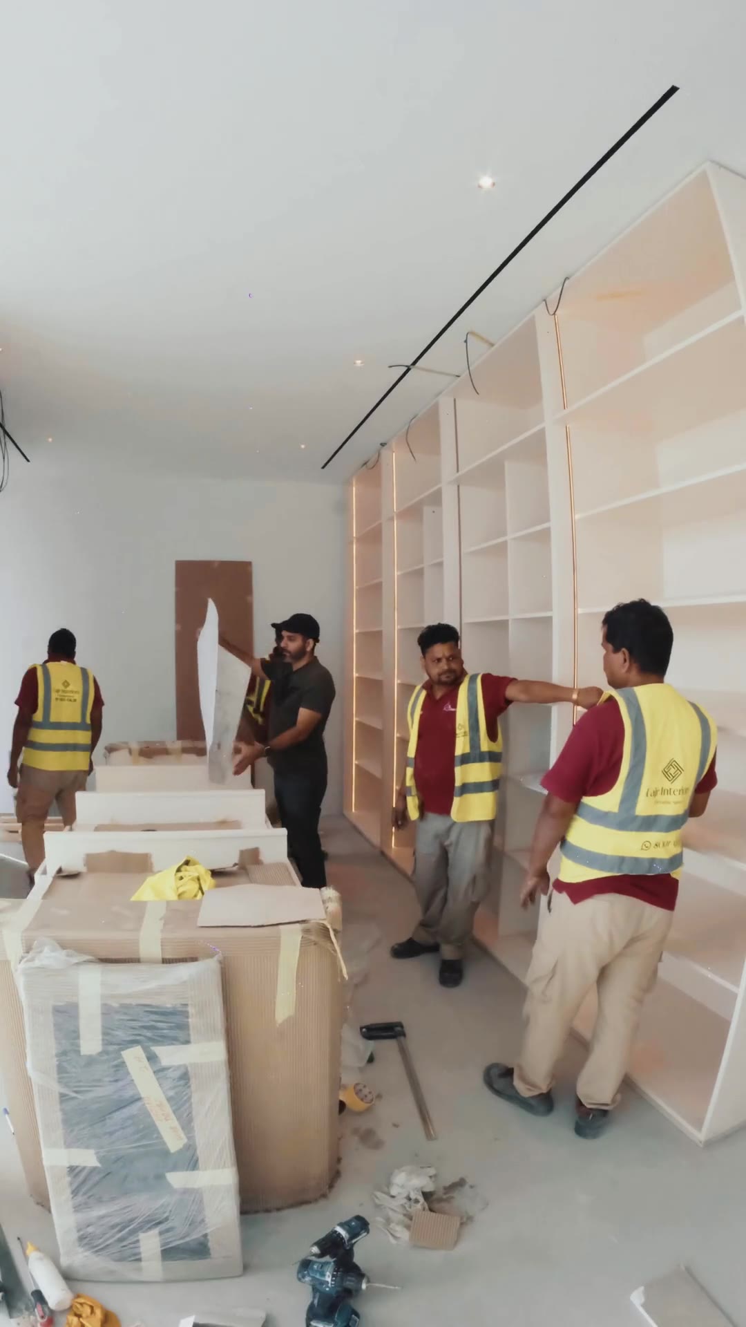 The Fajr Interiors team on site in a villa, fitting lit joinery shelving, Dubai